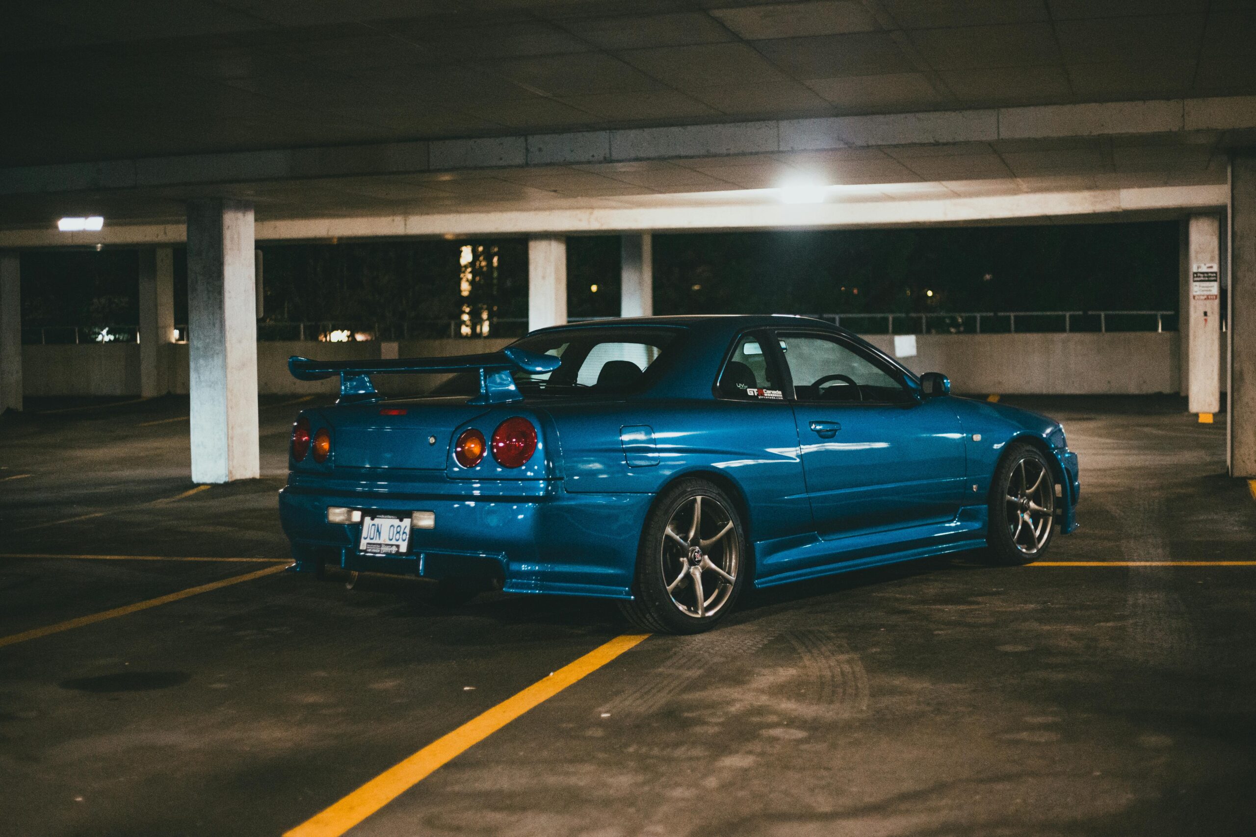 Projects A sleek blue Nissan Skyline sports car parked in an underground garage at night.